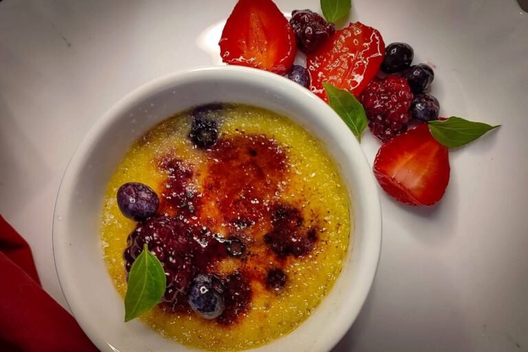 Creme brûlée com crosta caramelizada e frutas vermelhas frescas.
